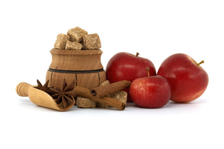 Red apples near sugar, cinnamon sticks and anise stars placed in wooden scoop. Baking apple pie concept isolated on whiteの写真素材