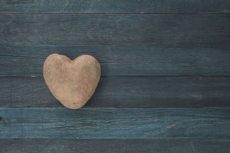 Heart-shaped potato on blue wooden vintage background, top view with copy spaceの写真素材