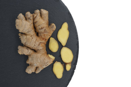 Ginger rhizome with slices on round stone slate coaster. Top view with free copy space for your textの写真素材