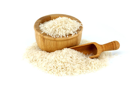 Dry long-grain rice in wooden bowl and wooden scoop isolated on white backgroundの写真素材