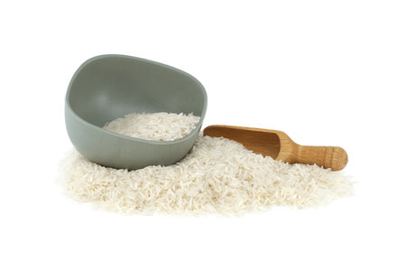 Long-grain rice in bowl and wooden scoop isolated on white backgroundの写真素材