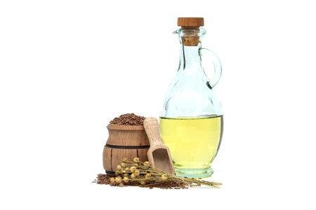 Linseed oil in glass decanter and flax seeds in wooden scoop and bunch of flax plants isolated on white background. Linum usitatissimum (Common Flax)の写真素材