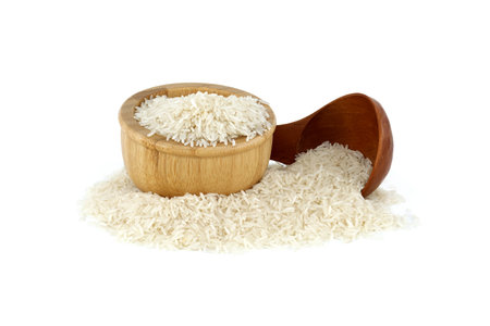 Uncooked long-grain rice in wooden bowl and wooden spoon isolated on white backgroundの写真素材