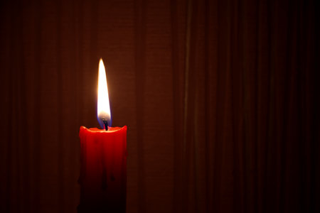 Single red candle burning alone in the dark red background. Conceptual image of peace, love, hope or patience in a panorama banner with free copy spaceの写真素材