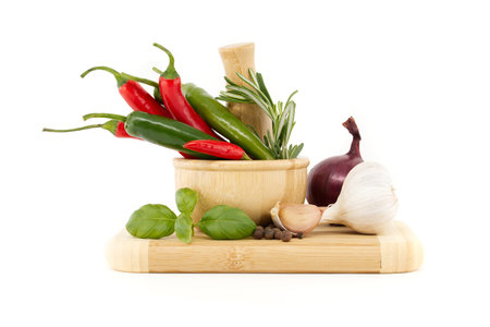 Chili peppers in wooden mortar, red onion, black pepper, basil sprig and garlic bulb isolated on white background. Spices, herbs and flavoring theme still lifeの写真素材