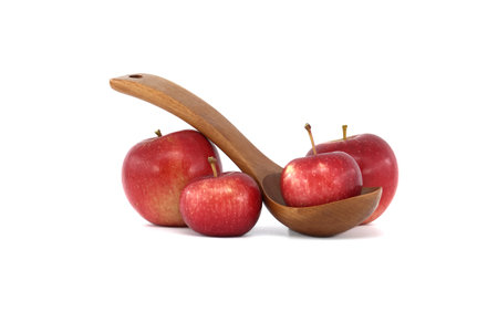 Red apples, one placed in a carved wooden spoon isolated on a white backgroundの写真素材