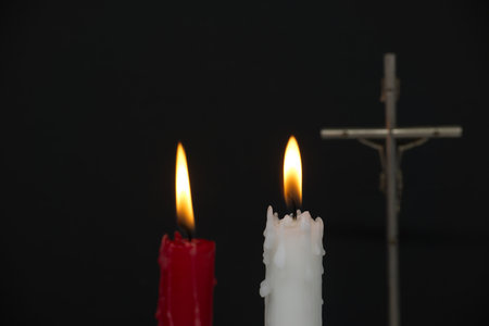 Burning candles and Christian cross against a black background with free copy space for textの写真素材