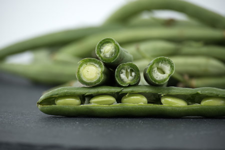 Heap of cut green beans on black stone table over white background. Organic and diet foodの写真素材