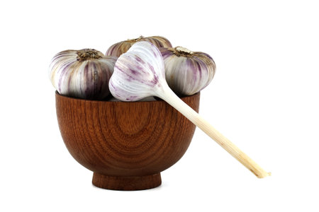 Freshly harvested garlic bulbs in wooden bowl isolated on white backgroundの写真素材
