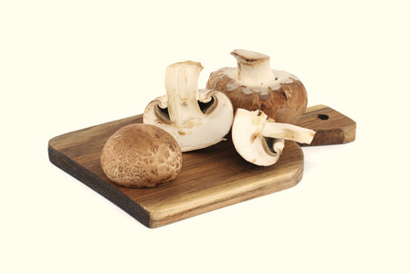 Fresh Baby Bella or Cremini whole mushrooms on wooden cutting board isolated on white backgroundの写真素材