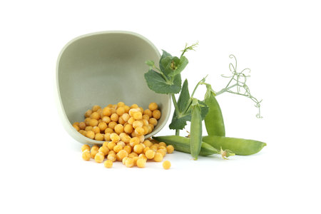 Fresh green garden peas and a bowl filled with dried whole yellow peas isolated on white backgroundの写真素材