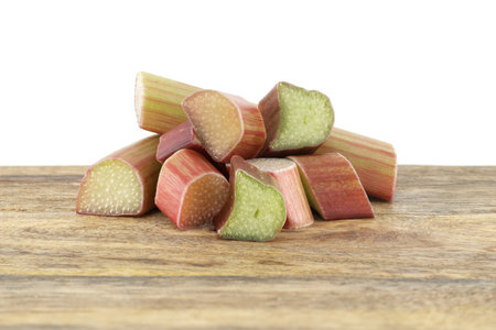 Variety of rhubarb stalks of varying colors from pale green to deep red on wooden cutting board isolated on white backgroundの写真素材