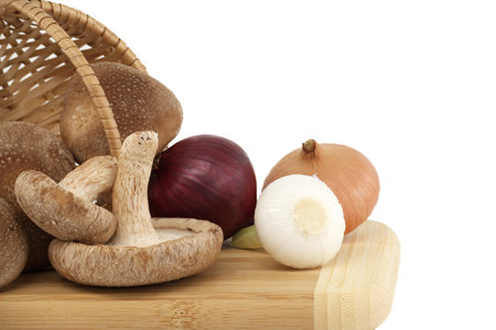 Fresh shiitake mushrooms, various onions on a wooden cutting board isolated on white background. Fungi recipes and medicinal herbsの写真素材