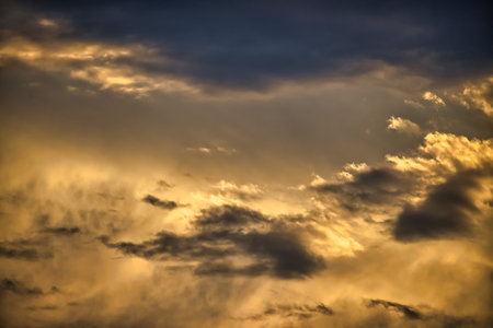 Sky with clouds which carry a dominant golden hue indicative a sunrise or sunset cumulus formation suggests a dynamic and dramatic sky with the sun either rising or setting in the backdropの写真素材