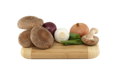Fresh shiitake mushrooms, various onions on a wooden cutting board isolated on white background. Fungi recipes and medicinal herbsの写真素材