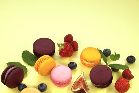 Array of macaroons, coming in shades of yellow, pink, and other colors, are carefully arranged and dominate the visual composition with free space for text and full depth of fieldの写真素材