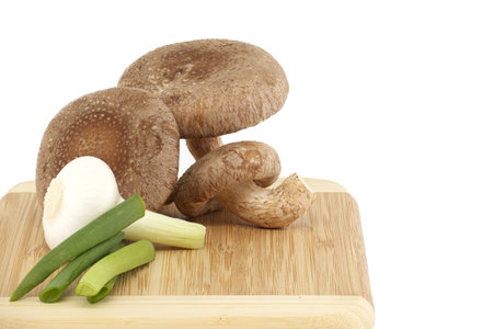Shiitake mushrooms and various onions on a wooden cutting board isolated on white background. Recipes and medicinal herbsの写真素材