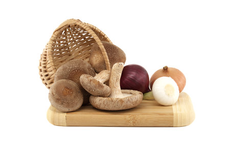 Shiitake mushrooms and various kinds of onions on a wooden cutting board over on white background. Recipes and medicinal herbsの写真素材