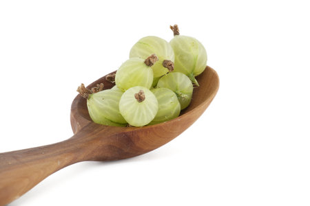 Green ripe gooseberries in a wooden spoon isolated on white backgroundの写真素材