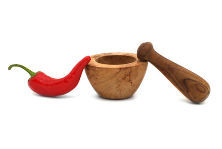 Fresh red chili pepper and old rustic wooden pestle with mortar isolated on a white backgroundの写真素材