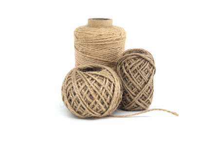 Three spools of jute twine isolated on white background, each varying in size, made from natural...