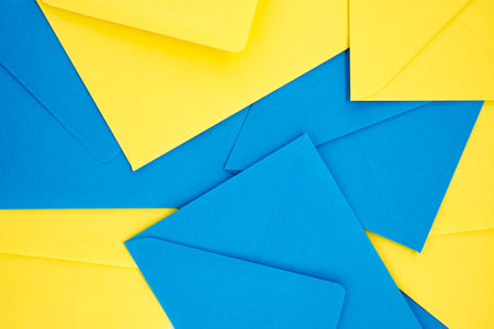 Blue and yellow paper envelopes organized in a symmetrical pattern gives the appearance of a three-dimensional, exploding geometry that adds a sense of depth and vibrancyの写真素材