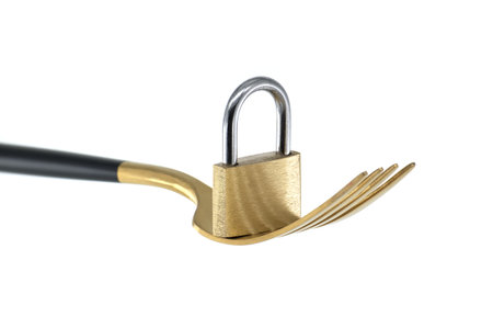 Fasting diet concept with gold fork and shiny gold padlock isolated on white backgroundの写真素材
