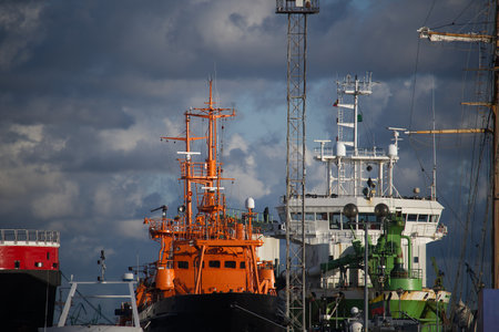 Cargo ships are docked in the harbor beneath a striking sky, highlighting industrial shipping...