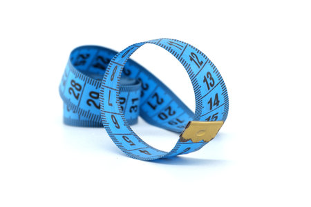 Close-up photo of a blue measuring tape neatly rolled up against a plain white backdrop, used for measurements and tailoring.の写真素材
