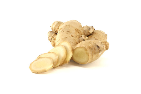 Close-up of fresh ginger root and slices isolated on a white background, highlighting its natural...