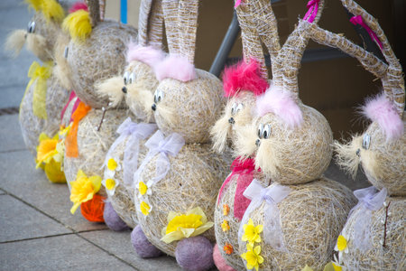 A line of whimsical Easter bunny decorations handmade with straw and colorful accents, perfect for...