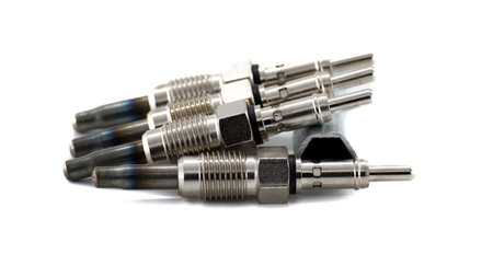 A close-up shot displays several automotive glow plugs, showcasing their metallic construction and...