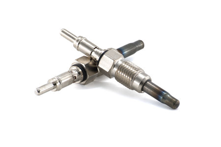 Two new glow plugs lie on a white surface, highlighting the intricate metal components and their...