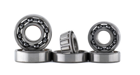 Group of new shiny metal ball bearings of different sizes standing and laying on white background, representing spare parts, industry, mechanics and engineeringの写真素材