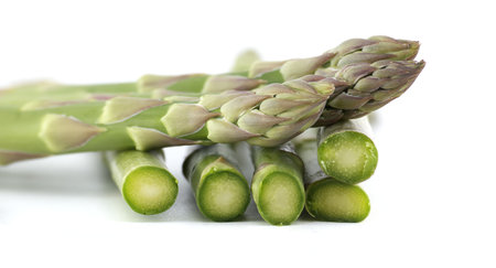 Fresh asparagus spears, some cut, against a bright white background, ideal for illustrating healthy eating and culinary concepts.の写真素材