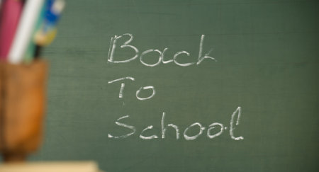 A chalkboard with the words 'Back to School' written in white chalk, pencils blurred in foreground.の写真素材