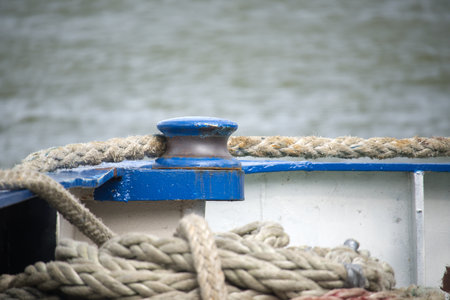 Detailed view of a rope tied to a boat's cleat, with soft focus background showcasing water,...