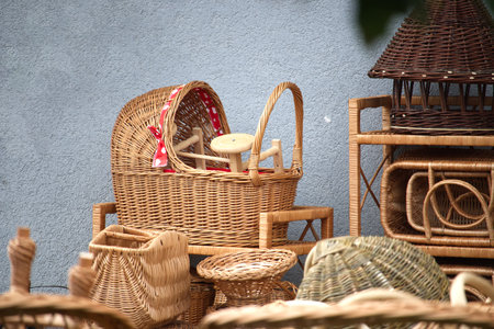 A collection of woven wicker baskets and rattan furniture arranged against a blue textured wall....