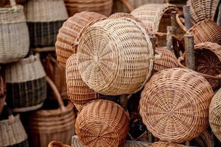 A showroom of round wicker baskets in natural tones, stacked on weathered wooden posts. Perfect for home dÃ©cor, craft markets, or rustic interiors, illustrating traditional basket weaving and artisanal craftsmanship.の写真素材
