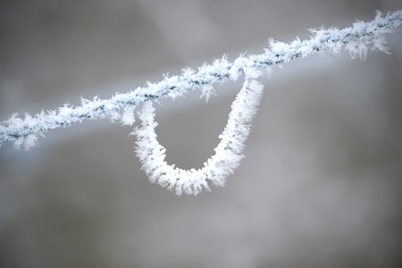 Frost-coated rope loop suspended in a frosty, hazy background. The ice crystals create delicate...