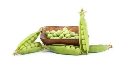 Vibrant green peas in pods spill from a wooden bowl, showcasing fresh garden produce perfect for...
