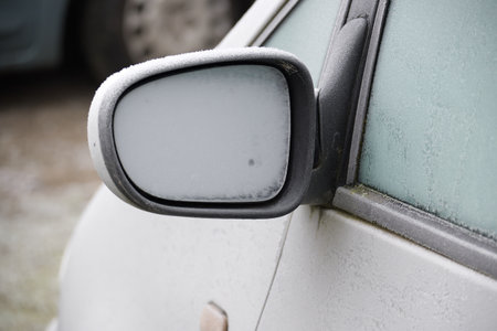 Close-up of a frosted car side mirror, highlighting winter weather and icy glass. Perfect for automotive, outdoor, and travel themes with a chilly, seasonal mood.の写真素材