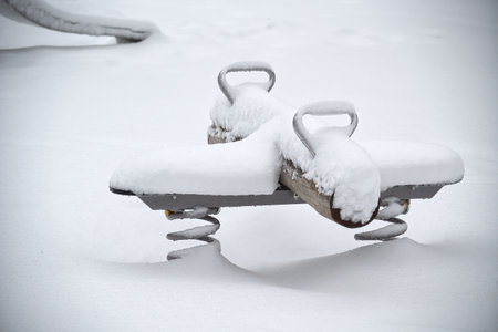 A children's playground is covered in snow, creating a serene and peaceful winter sceneの写真素材