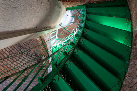 Spiral green staircase built from steel upwards view inside old building built of visible bricks