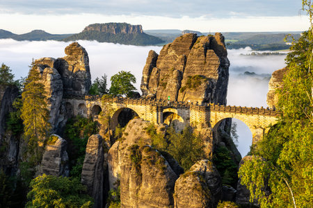 Bastei bridge stands majestically at sunrise in Saxon Switzerland, surrounded by the stunning Elbe Sandstone Mountains and enchanting mist rising from the valleys below.の写真素材
