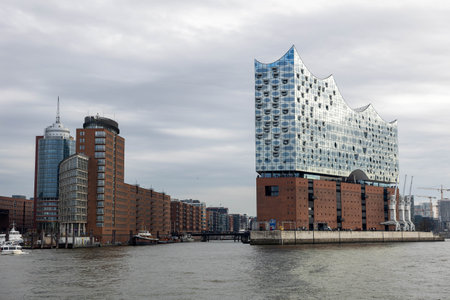 Impressive modern structures of Elbphilharmonie line the waterfront in Hamburg, Germany. The unique designs contrast with historical buildings, creating a vibrant urban landscape by the river.の写真素材