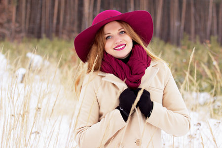 Smiling young, beautiful and stylish red hair girl in coat and hat in the forest. Fashion.の写真素材