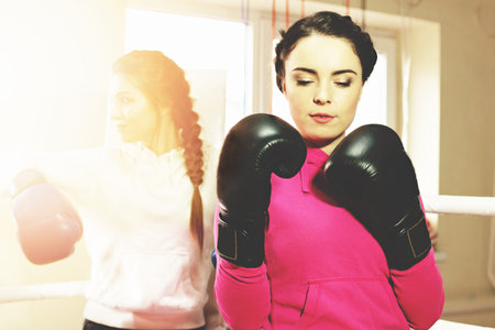 Portrait of beautiful boxing girl posing with black boxing gloves. Training at the gym. Sporty female doing boxing exercise.の写真素材