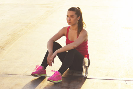 Relaxing after jogging. Horizontal shot of beautiful young woman in sports clothing looks...