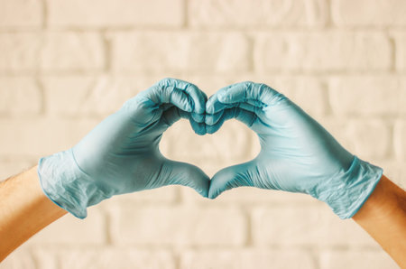 Men hands in protective gloves showing heart symbols in hospital. Doctor surgeon in medical gloves...